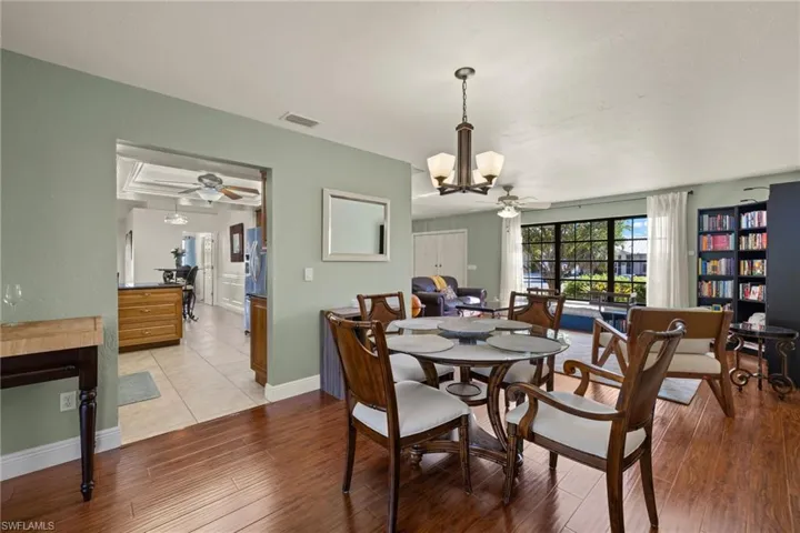 Dining room with ceiling fan with notable chandelier and light hardwood / wood-style flooring