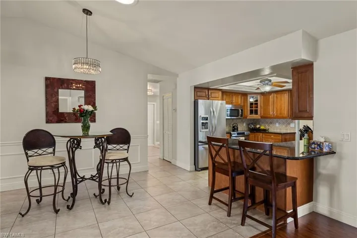 Kitchen with ceiling fan with notable chandelier, appliances with stainless steel finishes, decorative light fixtures, kitchen peninsula, and a breakfast bar area
