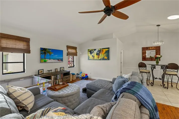 Living room with light hardwood / wood-style floors, ceiling fan, and lofted ceiling