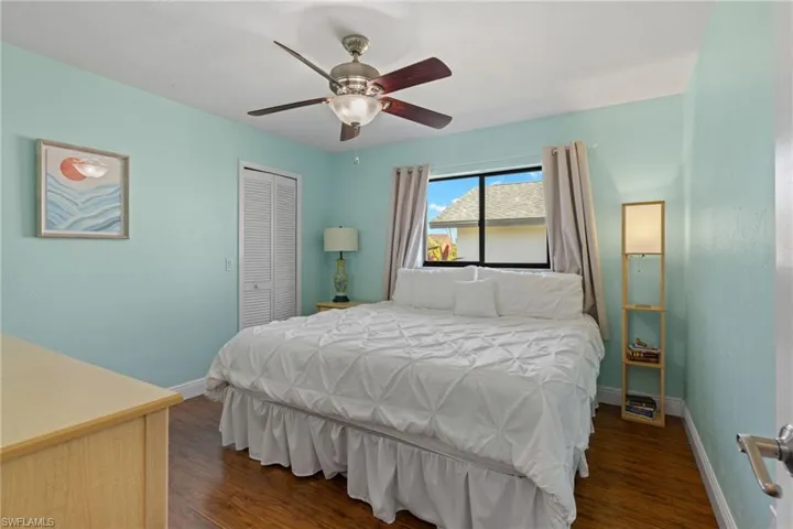 Bedroom with dark hardwood / wood-style flooring, ceiling fan, and a closet