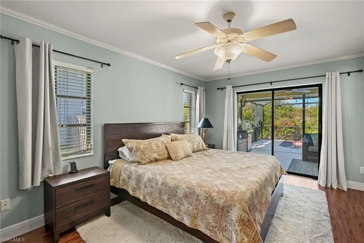 Bedroom featuring access to exterior, hardwood / wood-style flooring, multiple windows, and ceiling fan