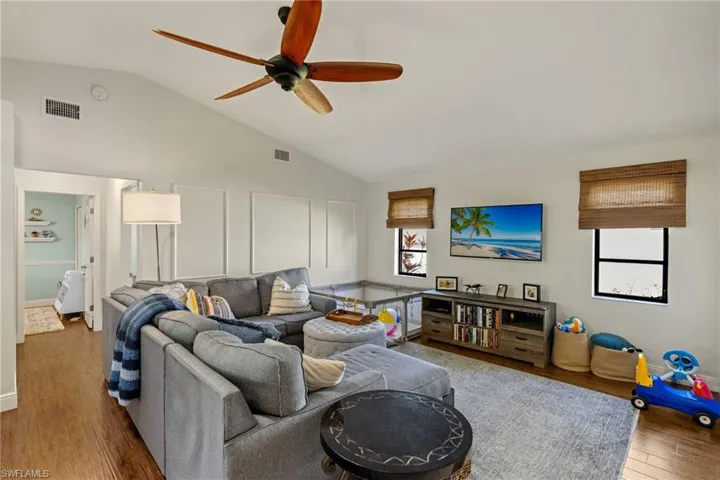 Living room featuring a wealth of natural light, hardwood / wood-style floors, ceiling fan, and vaulted ceiling