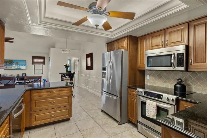 Kitchen with a tray ceiling, backsplash, stainless steel appliances, and decorative light fixtures