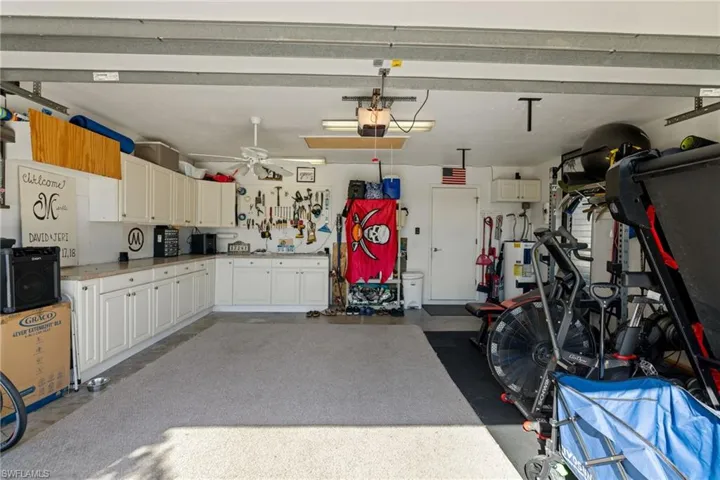 Garage with a workshop area, ceiling fan, water heater, and a garage door opener