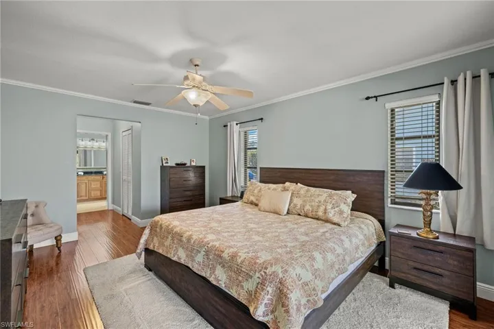 Bedroom featuring hardwood / wood-style floors, ensuite bathroom, ceiling fan, and ornamental molding