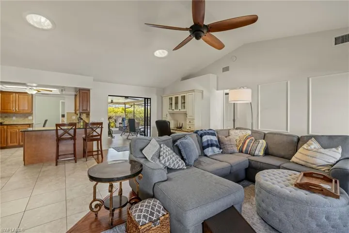 Tiled living room featuring high vaulted ceiling and ceiling fan