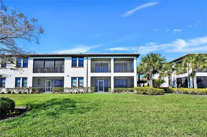 Rear view of property featuring a sunroom, stucco siding, a yard, and a balcony