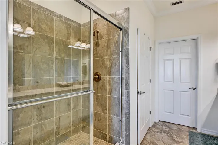 Bathroom featuring a stall shower and crown molding