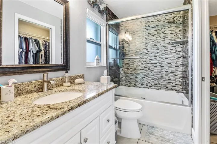 Full bathroom featuring tile floors, bath / shower combo with glass door, large vanity, and toilet