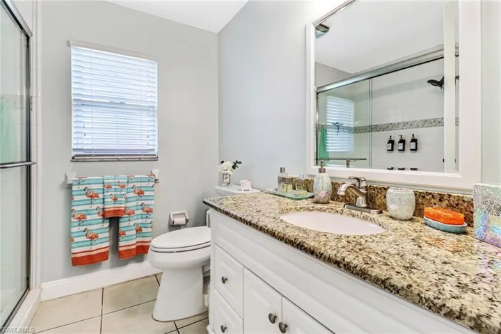 Bathroom featuring a shower with shower door, tile floors, large vanity, and toilet