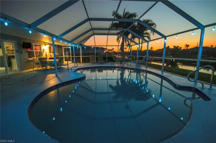 Pool at dusk featuring a patio and a lanai