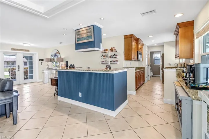 Kitchen with a healthy amount of sunlight, french doors, a breakfast bar area, and light tile floors