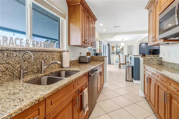 Kitchen with stainless steel appliances, light stone countertops, a wealth of natural light, and backsplash