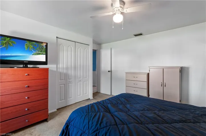 Room featuring neutral wall finishes, carpeted flooring, a ceiling fan with integrated lighting, and dual bifold closet doors