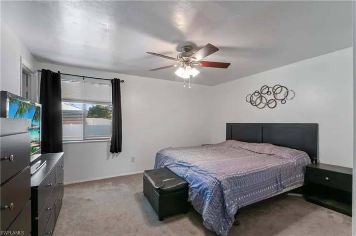 Neutral-tone wall finish, neutral wall-to-wall carpeting, and a multi-blade ceiling fan with an integrated light fixture