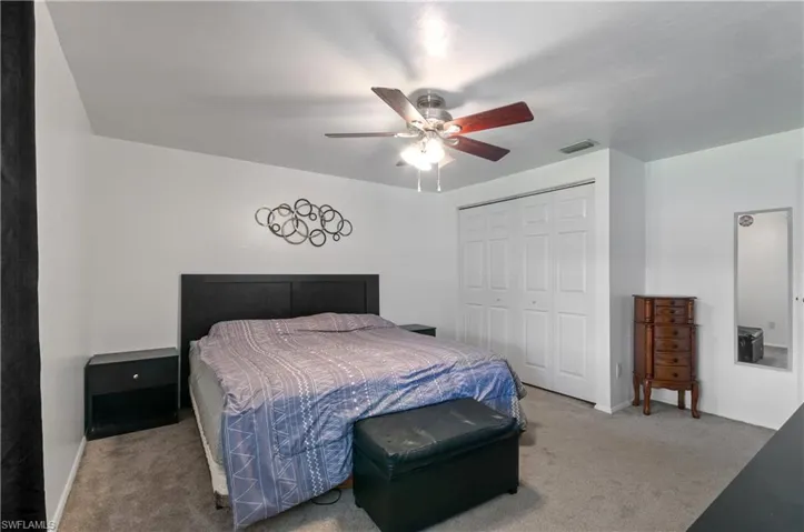 Interior room featuring neutral carpeting, a dual-lighted ceiling fan, and a white bifold closet