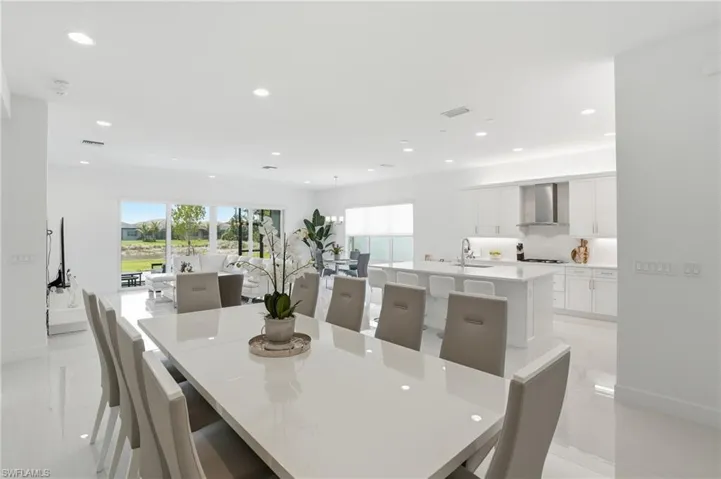 Open-concept interior featuring large-format tile flooring, recessed ceiling lighting, and a kitchen equipped with a quartz-topped center island and stainless steel range hood