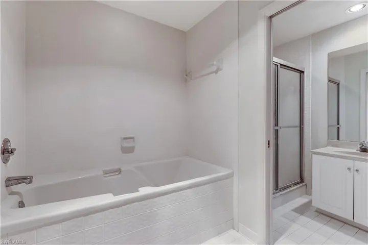 primary bath with dual vanities and a separate tub