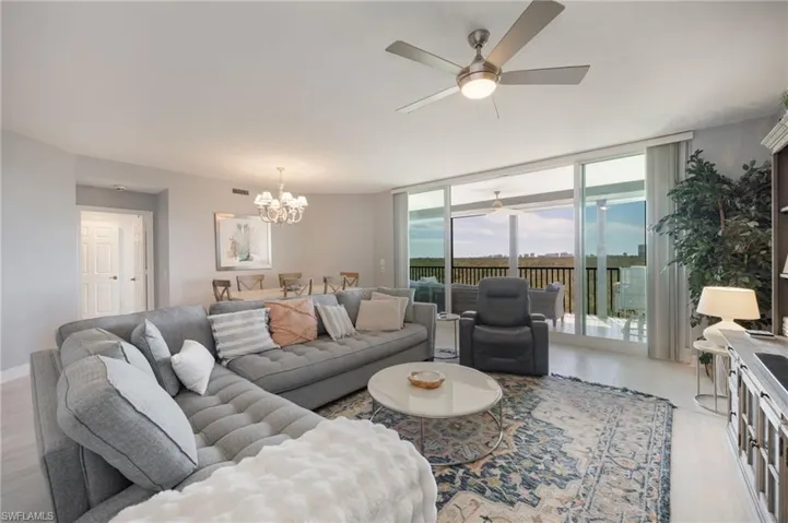 Living area with wood finished floors, a ceiling fan, suspended lighting, and expansive windows