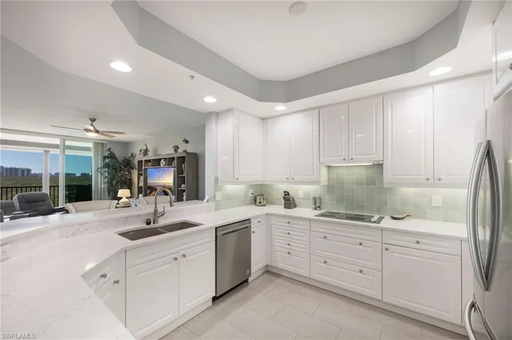 Kitchen featuring white cabinetry, light stone counters, stainless steel appliances, recessed lighting, and a ceiling fan