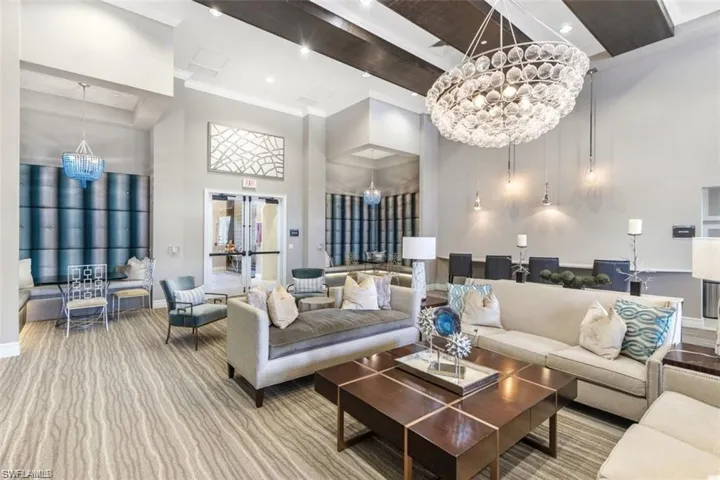 Living room with carpet flooring, crown molding, a towering ceiling, and an inviting chandelier