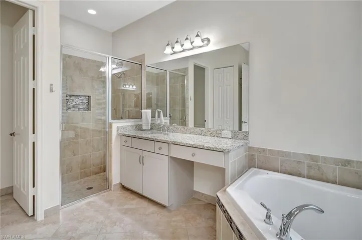 Bathroom with vanity, tile patterned floors, and plus walk in shower