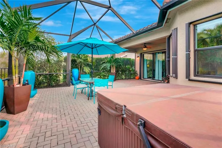View of patio featuring a lanai, ceiling fan, and a hot tub