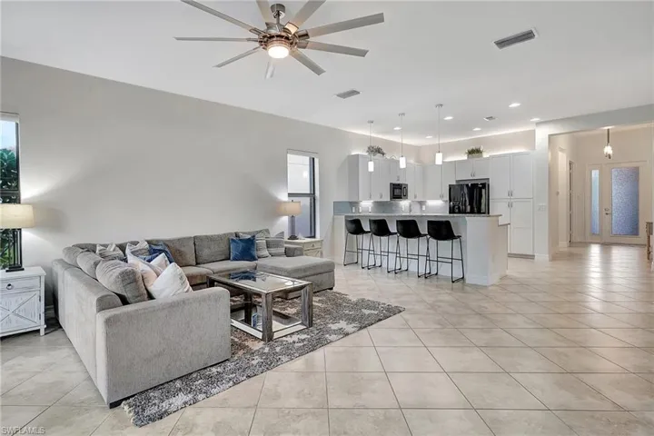 Living room featuring a wealth of natural light, light tile patterned floors, and ceiling fan