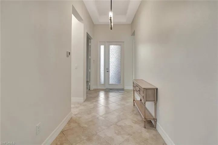 Foyer with light tile patterned flooring and a raised ceiling
