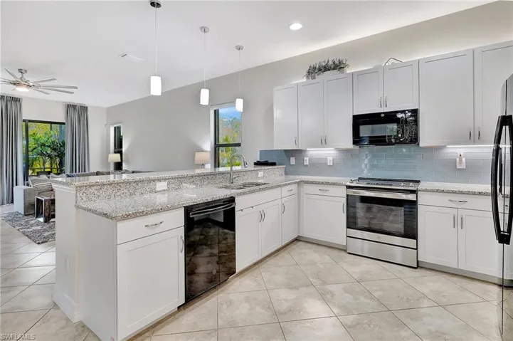 Kitchen featuring white cabinets, black appliances, sink, hanging light fixtures, and kitchen peninsula