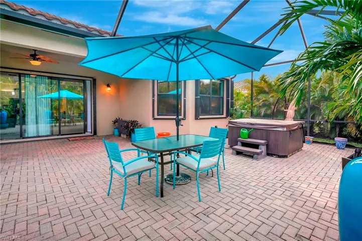 View of patio / terrace with a lanai, ceiling fan, and a hot tub