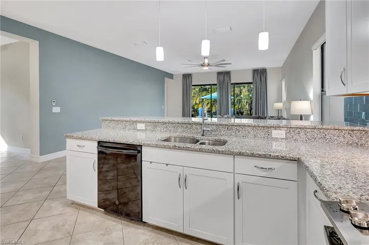 Kitchen featuring light stone countertops, white cabinetry, tasteful backsplash, and sink
