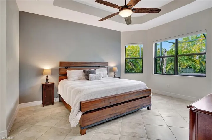 Tiled bedroom featuring ceiling fan and a tray ceiling