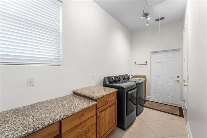 Laundry area has granite countertops, sink and a large pantry/storage area. Natural light fills this space.