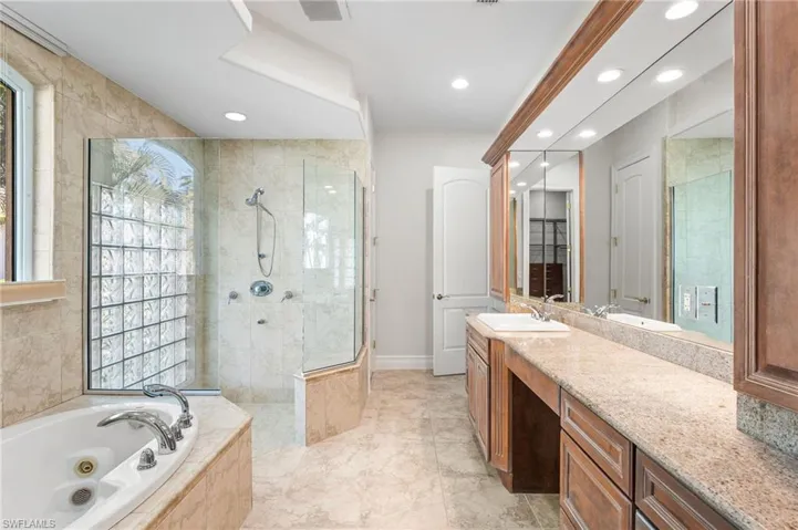 Your primary bath offers a walk in shower with floor to ceiling tile, a lovely jetted soaking garden tub and a granite countertop! Recessed lighting. Glass brick in the shower lets natural light in!