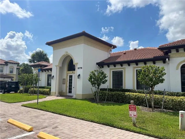 Mediterranean / spanish-style Club house with stucco siding, a front yard, and a tile roof