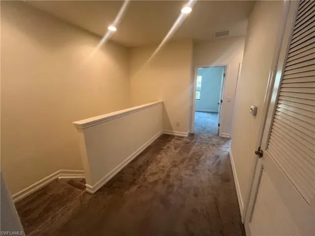 Hallway featuring carpet floors and an upstairs landing