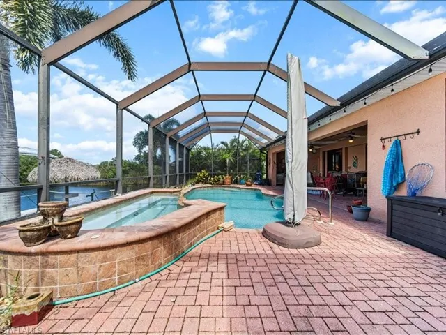View of swimming pool with a sunroom, a lanai, a patio area, a pool with connected hot tub, and a ceiling fan