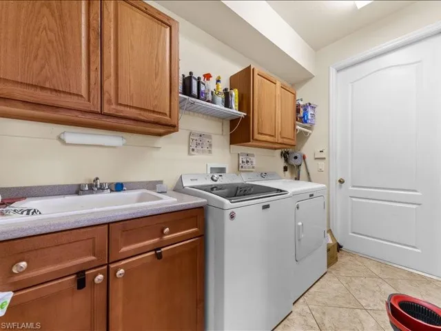 Laundry area featuring light tile patterned flooring, cabinet space, and washing machine and clothes dryer