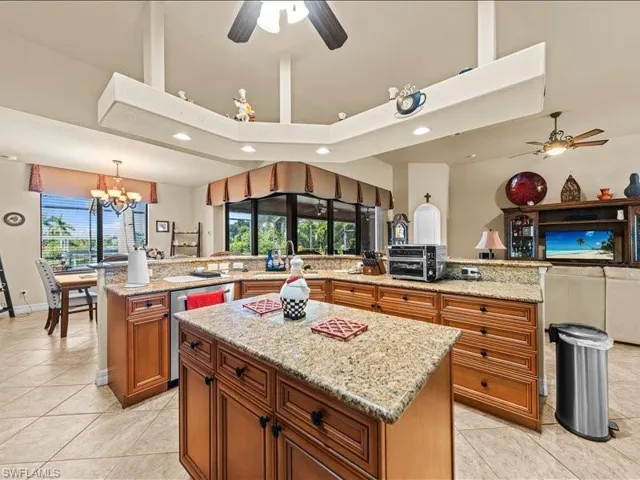 Kitchen featuring a ceiling fan, open floor plan, brown cabinetry, light stone countertops, and recessed lighting