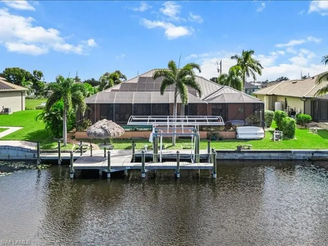 Dock featuring boat lift, glass enclosure, a sunroom, and a water view