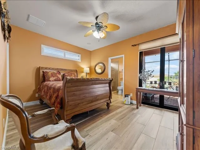 Bedroom with light wood finished floors, ceiling fan, and ensuite bathroom