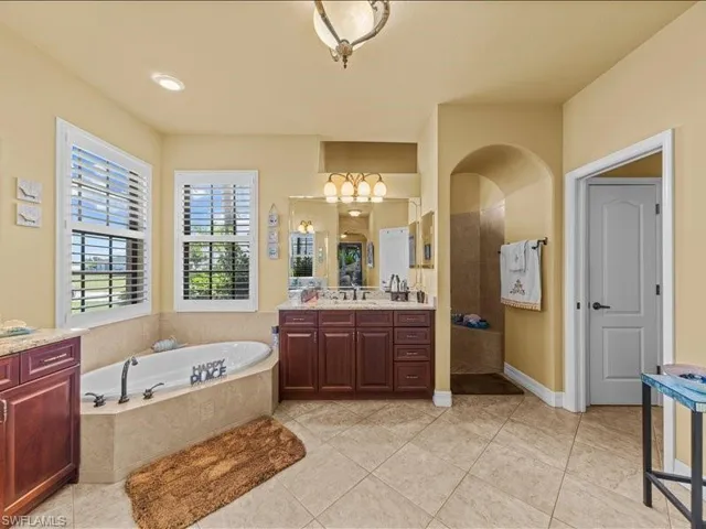 Bathroom featuring a bath, vanity, light tile patterned floors, a walk in shower, and recessed lighting