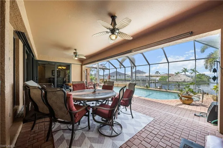 Sunroom / solarium featuring a ceiling fan, outdoor dining space, a patio, and a residential view