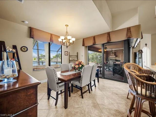 Dining area featuring healthy amount of natural light, a chandelier, light tile patterned flooring, and ceiling fan