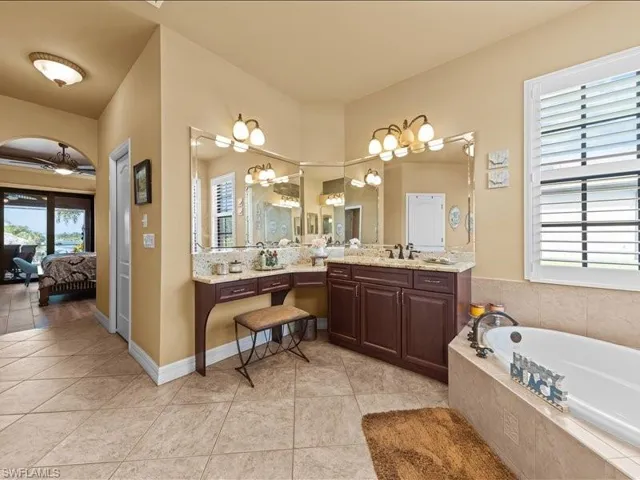 Ensuite bathroom with a bath, vanity, light tile patterned flooring, and tasteful backsplash