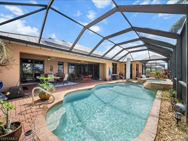 View of swimming pool featuring glass enclosure, a patio, a sunroom, a ceiling fan, and a pool with connected hot tub
