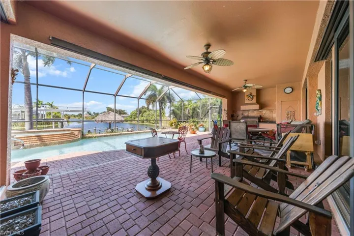 View of patio / terrace featuring ceiling fan, a lanai, a sunroom, a water view, and a pool with connected hot tub