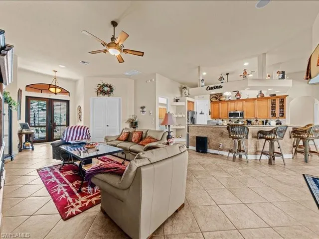 Living room featuring arched walkways, french doors, light tile patterned flooring, ceiling fan, and recessed lighting