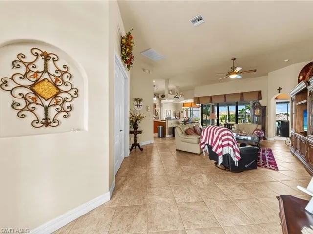 Living room featuring light tile patterned floors, a ceiling fan, and arched walkways